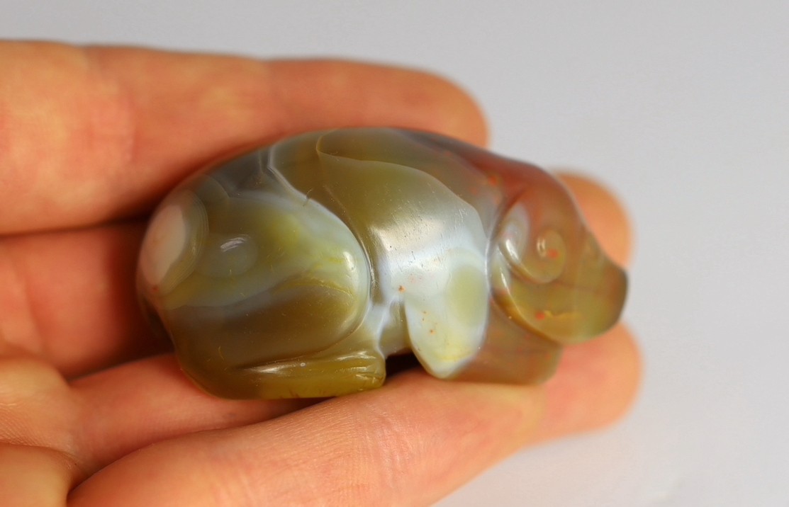 A Chinese banded agate figure of a recumbent pig, 18th/19th century, 5.4cm long, wood stand